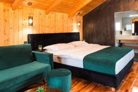 Chambre au Halicanum Glamping Peaceful Retreat Resort 3 en Croatie avec murs en bois, lit double et canapé vert.