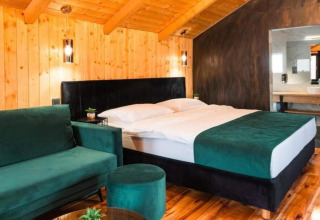 Chambre au Halicanum Glamping Peaceful Retreat Resort 3 en Croatie avec murs en bois, lit double et canapé vert.