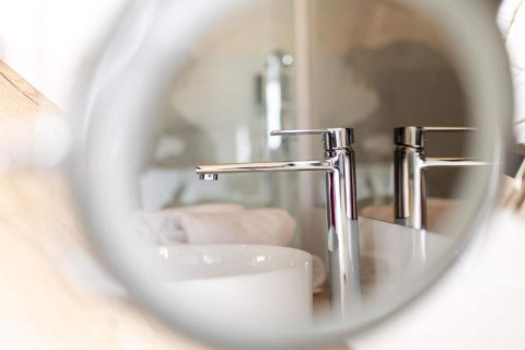Reflet d'un robinet de salle de bain moderne au Halicanum Glamping Peaceful Retreat Resort 3 en Croatie.
