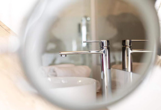 Reflet d'un robinet de salle de bain moderne au Halicanum Glamping Peaceful Retreat Resort 3 en Croatie.