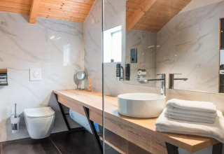 Salle de bain moderne avec plafond en bois, toilettes suspendues et vasque élégante au Halicanum Glamping Peaceful Retreat Resort 3 en Croatie.