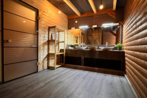 Salle de bain moderne avec murs en bois, double vasque et grands miroirs au Halicanum Glamping en Croatie.