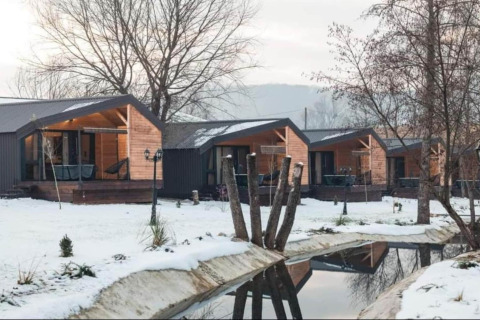 Halicanum Glamping Peaceful Retreat Resort 3 avec chalets en bois modernes, paysage enneigé et ruisseau paisible.
