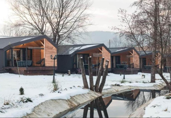 Halicanum Glamping Peaceful Retreat Resort 3 avec chalets en bois modernes, paysage enneigé et ruisseau paisible.