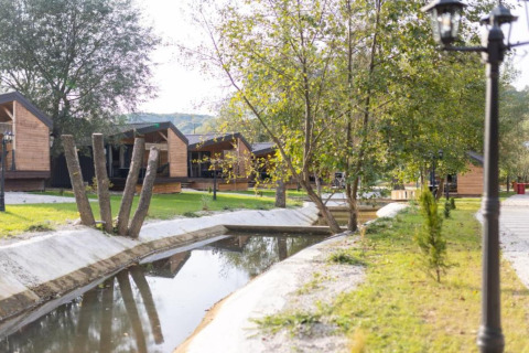 Chalets en bois près d’un canal paisible avec arbres au Halicanum Glamping Peaceful Retreat Resort 3 en Croatie.