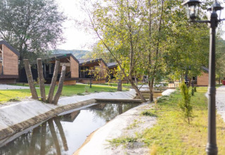 Chalets en bois près d’un canal paisible avec arbres au Halicanum Glamping Peaceful Retreat Resort 3 en Croatie.