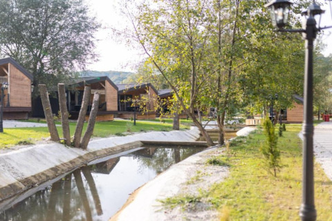 Chalets en bois près d’un petit canal verdoyant au Halicanum Glamping Peaceful Retreat Resort en Croatie.