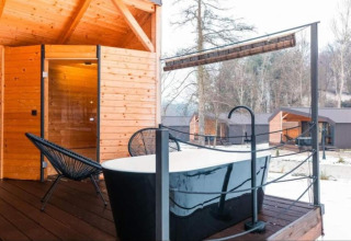 Baignoire extérieure et terrasse en bois au Halicanum Glamping Peaceful Retreat Resort 16 en Croatie, avec cabanes autour.
