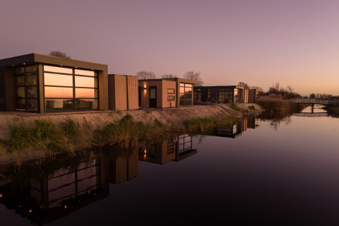 Case vacanza moderne sull'acqua al MarinaPark Beach Resort Soal, Friesland, Paesi Bassi, al tramonto.