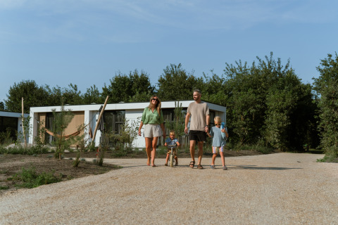 En familie går på en grusvej foran en moderne feriebolig i MarinaPark Residentie Bloemendaal, Holland.