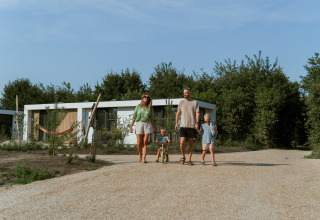 A family walks on a gravel path in front of a modern holiday home at MarinaPark Residentie Bloemendaal, Netherlands.