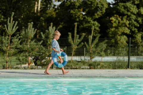 Un bambino cammina vicino a una piscina con un salvagente al MarinaPark Residentie Bloemendaal in Olanda Settentrionale, Paesi Bassi.