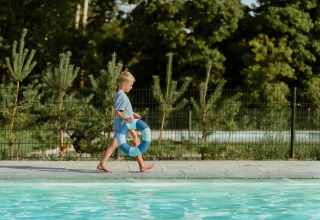 En dreng går ved en pool med en redningskrans på MarinaPark Residentie Bloemendaal i Nordholland, Holland.