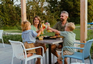 Family enjoying a meal and toasting drinks outside at MarinaPark Residentie, Bloemendaal, Netherlands.