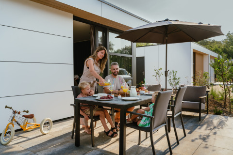 Family enjoys outdoor dining at a table under an umbrella at MarinaPark Residentie, Bloemendaal, Netherlands.