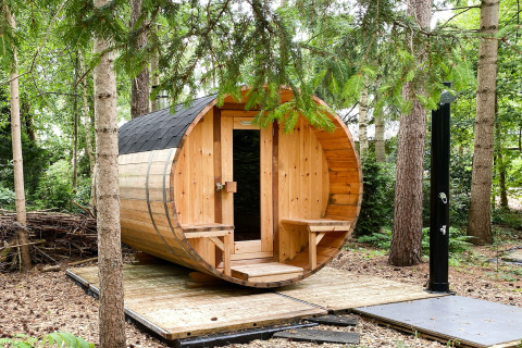 Een tonvormige houten buitensauna op een platform in het bos bij Dutch Cabin Houses C66 in Nederland