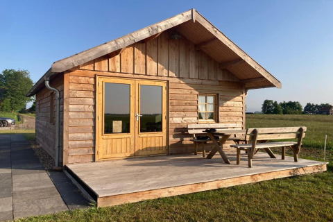 Houten huisje met veranda en zitje bij «Frisian Hideaway with Style» lodge in Nederland.