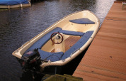 Kleine motorboot aangemeerd aan houten ponton bij Luxury chalet 55 in Nederland, rustig aan het water.