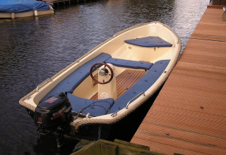 Piccola barca a motore ormeggiata a un molo in legno presso Luxury chalet 55 nei Paesi Bassi.