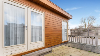 Terrasse extérieure du houseboat Luxury chalet 55 sur l’eau à Bantega, façade en bois, portes vitrées.