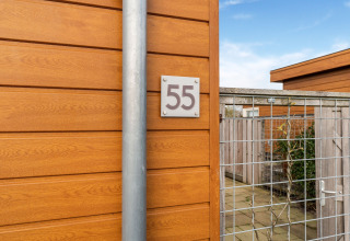 Entrada al Luxury Chalet 55 en los Países Bajos, con revestimiento de madera y una puerta de malla metálica.