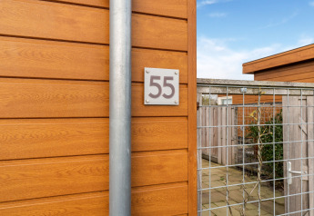 Entrada al Luxury Chalet 55 en los Países Bajos, con revestimiento de madera y una puerta de malla metálica.