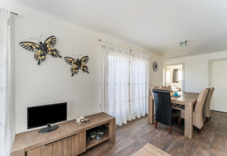 Luminoso comedor en una casa flotante en los Países Bajos, con muebles de madera y decoración de mariposas.