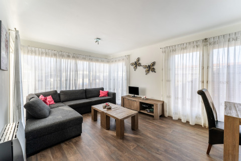 Lyst og moderne stue i Luxury chalet 55 med stor sofa, sofabord og dekorerende sommerfugle på væggen.
