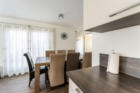 Comedor con seis sillas marrones, mesa de madera y encimera moderna en casa flotante en Holanda.