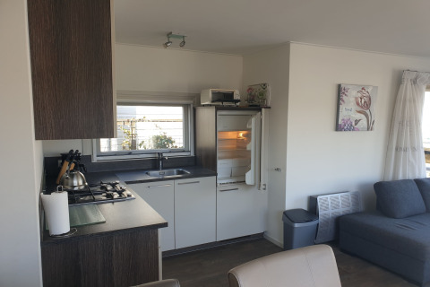 Moderne køkken- og stueområde på en husbåd ved Luxury chalet 55 i Holland med vindue og sofa.