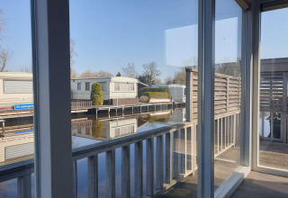 View from houseboat Luxury chalet 55 in the Netherlands, showing the terrace and calm water reflection.