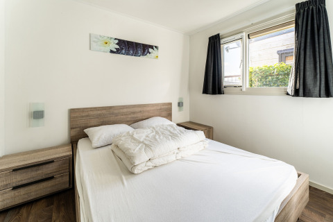 Camera luminosa con letto matrimoniale, comodini e finestra su una houseboat al Luxury chalet 55 nei Paesi Bassi.