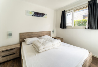 Dormitorio luminoso con cama doble, mesitas de noche y ventana en un barco casa en Luxury chalet 55, Países Bajos.