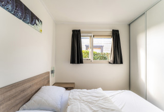 Lichte slaapkamer op woonboot Luxury chalet 55 in Nederland met tweepersoonsbed en raam.