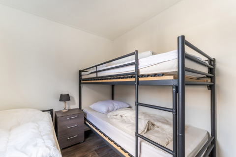 Slaapkamer op woonboot Luxury chalet 55 in Nederland met stapelbed, nachtkastje en eenpersoonsbed.