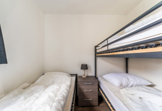 Chambre sur houseboat Luxury chalet 55 aux Pays-Bas avec un lit simple, un lit superposé et une table de nuit.