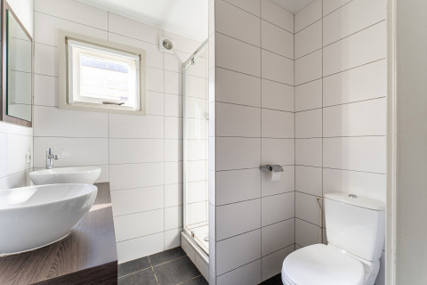 Baño moderno con lavabo doble, inodoro y ducha en una lujosa casa flotante en los Países Bajos.