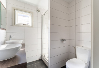 Baño moderno con lavabo doble, inodoro y ducha en una lujosa casa flotante en los Países Bajos.