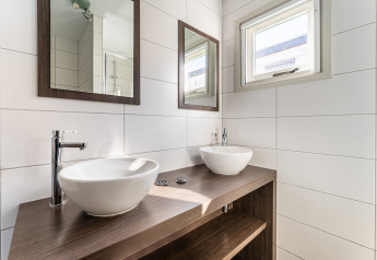 Baño moderno con dos lavabos, espejos y ventana en una casa flotante de lujo en los Países Bajos.