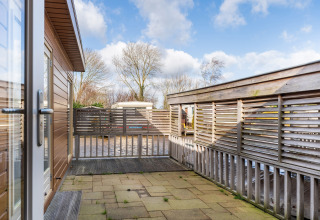 View from the terrace of Luxury chalet 55 houseboat in the Netherlands with modern fencing and blue sky.