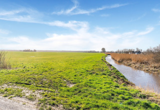 Foto de un campo verde con un canal y cielo azul, tomada cerca de Luxury chalet 55 en los Países Bajos.