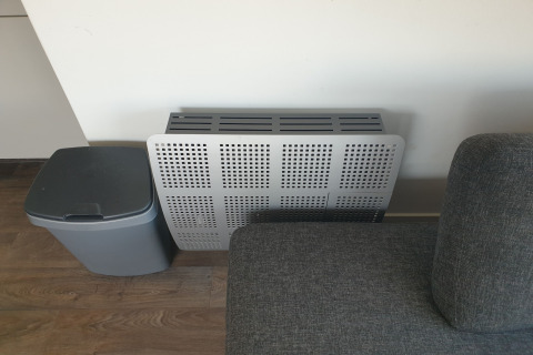 Moderne radiatorbekleding, grijze zetel en vuilnisbak in de living van houseboat Luxury chalet 55 in Nederland.