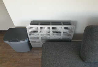 Graue Couch, moderner Heizkörperverkleidung und Abfalleimer in einem Hausboot, Luxury chalet 55, Niederlande.