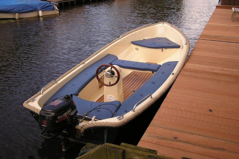 Ein kleines Motorboot ist an einem Holzsteg bei der Hausboot-Luxus-Chalet 55 in den Niederlanden vertäut.