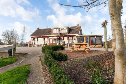 Luxe chalet 55 woonboot in Nederland, buitenaanzicht met tuin en picknicktafel op de voorgrond.