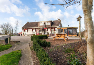 Casa flotante Luxury chalet 55 en los Países Bajos, vista exterior con jardín y mesa de picnic en primer plano.
