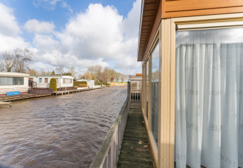 Vista desde la casa flotante Luxury chalet 55 en los Países Bajos, sobre un canal y casas flotantes vecinas.