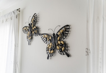 Arte de pared con dos mariposas de metal y piedras en Luxury chalet 55 houseboat en los Países Bajos.