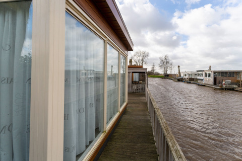 View from a houseboat with large windows and wooden deck on the water at Luxury chalet 54 Bantega, Netherlands.