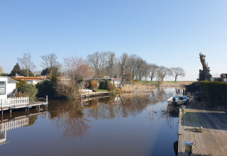 Idyllisk udsigt over kanal og husbåde ved Luxury chalet 54 Bantega, Holland, med båd og træer.